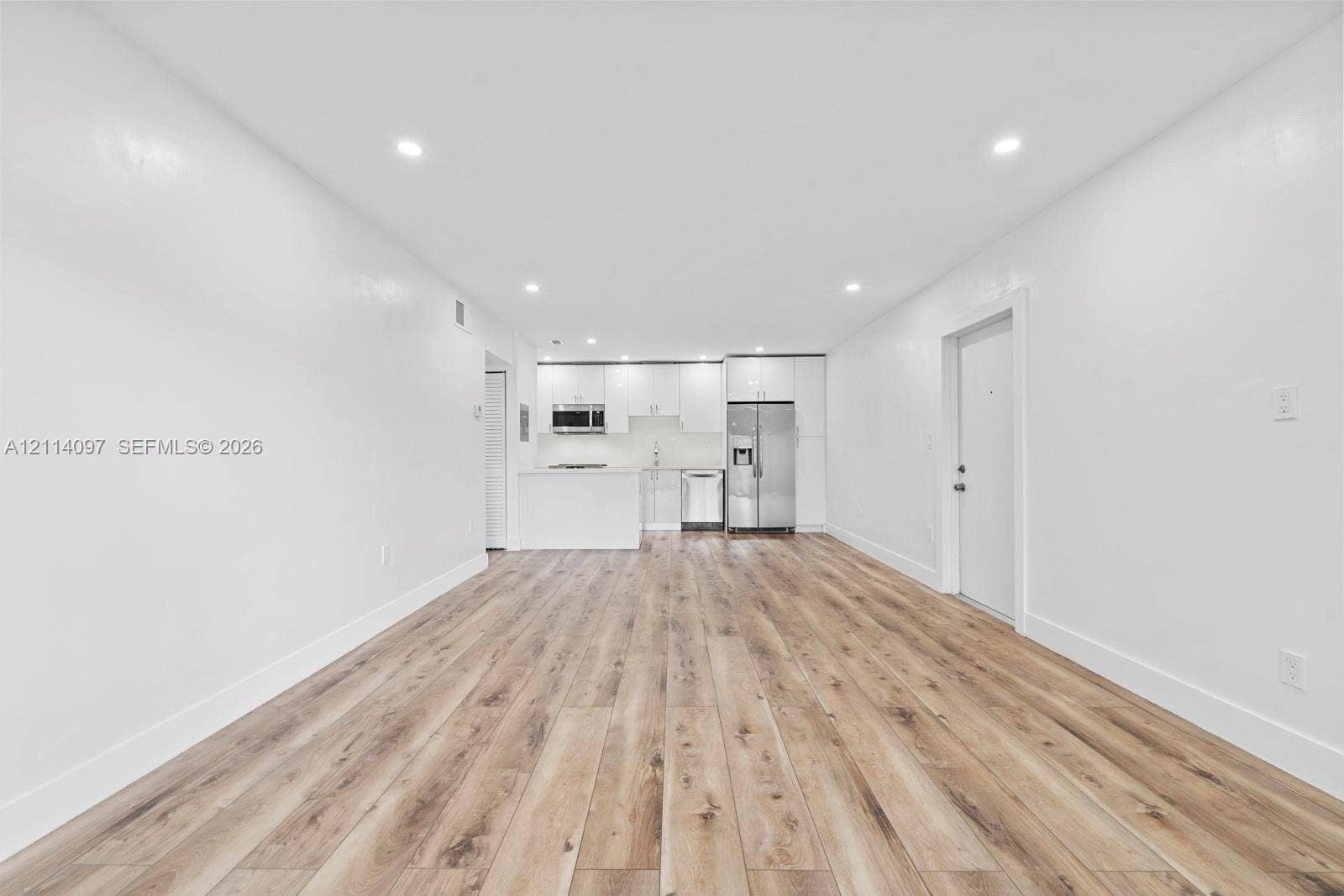 7905 SW 104th Street, #206H, Miami, FL 33156 Open-concept interior featuring wood-finish flooring, recessed lighting, and a kitchen equipped with stainless steel appliances, white cabinetry, and a peninsula