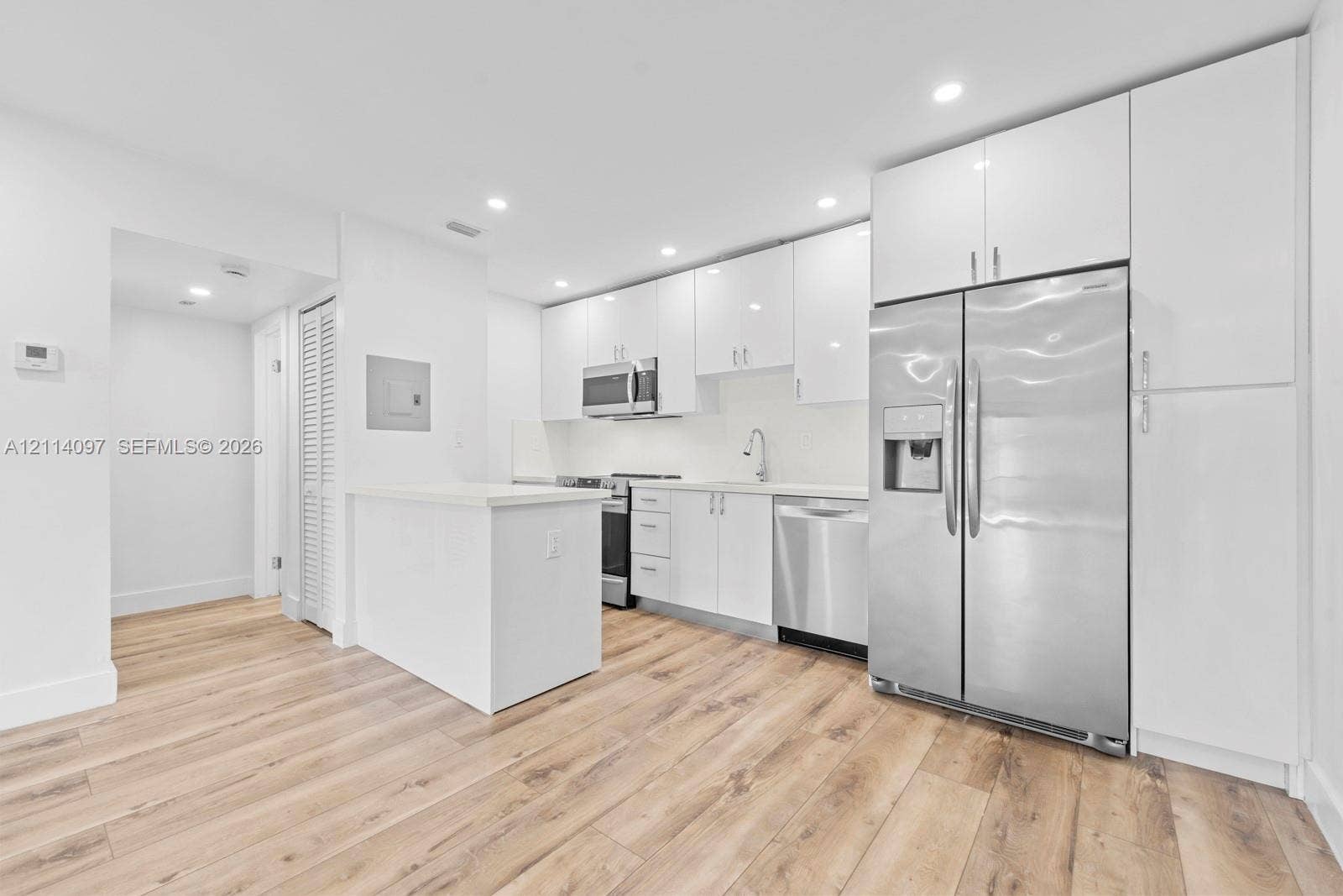 7905 SW 104th Street, #206H, Miami, FL 33156 Kitchen featuring white high-gloss cabinetry, stainless steel appliances, wood-finish flooring, quartz countertops, and recessed lighting