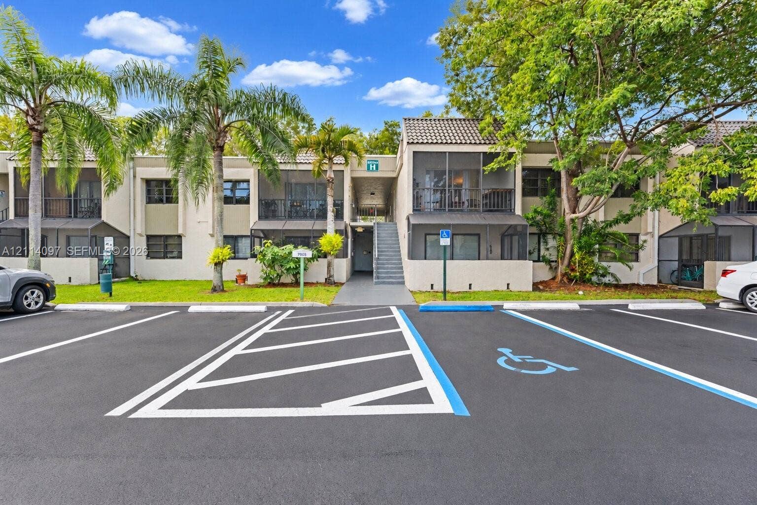 7905 SW 104th Street, #206H, Miami, FL 33156 Two-story exterior featuring a neutral stucco facade, tile roofing, screened-in balconies, and mature landscaping