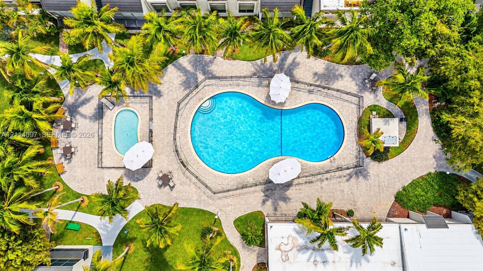 7905 SW 104th Street, #206H, Miami, FL 33156 Outdoor area featuring a freeform swimming pool, a separate secondary pool, paved decking, and mature palm trees