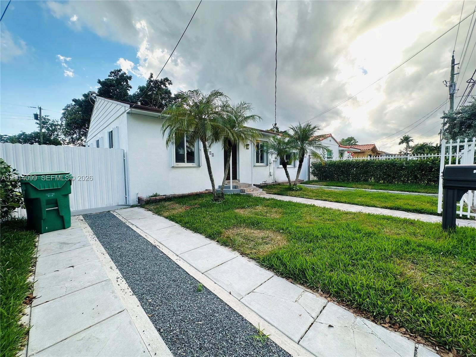 3052 SW 6th Street, Miami, FL 33135 Single-story exterior with white siding, dual-material paved driveway, and perimeter white fencing