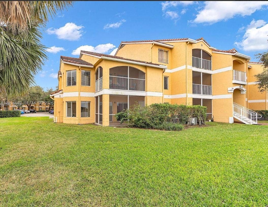 2485 NW 33rd Street, #1602, Oakland Park, Oakland Park, FL 33309 Stucco exterior featuring multi-level screened-in lanais, tile roofing, and metal stair railings, set against an expansive manicured lawn