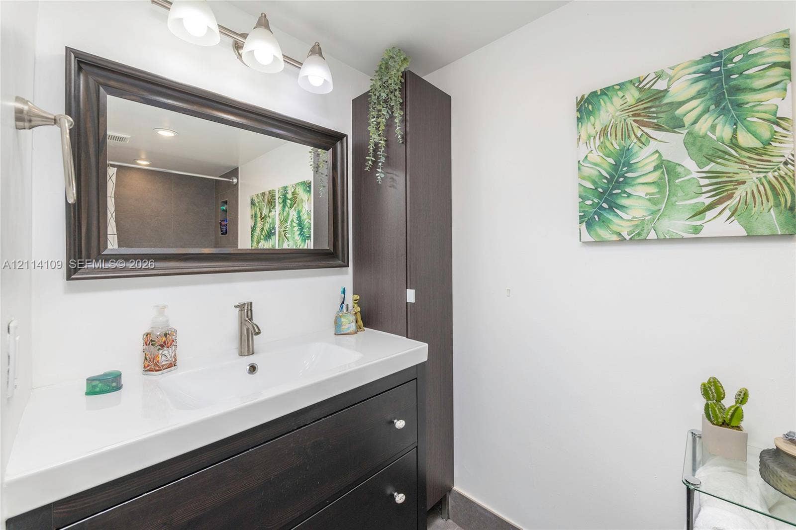 15761 SW 137th Avenue, #104, Miami, Miami, FL 33177 Bathroom vanity featuring dark wood-finish cabinetry, white countertop, integrated rectangular sink, brushed nickel faucet, and matching framed mirror with three-light fixture