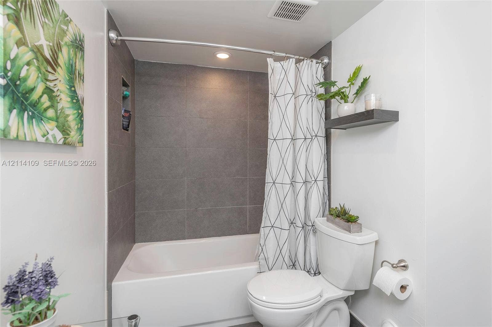 15761 SW 137th Avenue, #104, Miami, Miami, FL 33177 Bathroom featuring a soaking tub, floor-to-ceiling charcoal tile surround, integrated shower niche, and a wall-mounted floating shelf