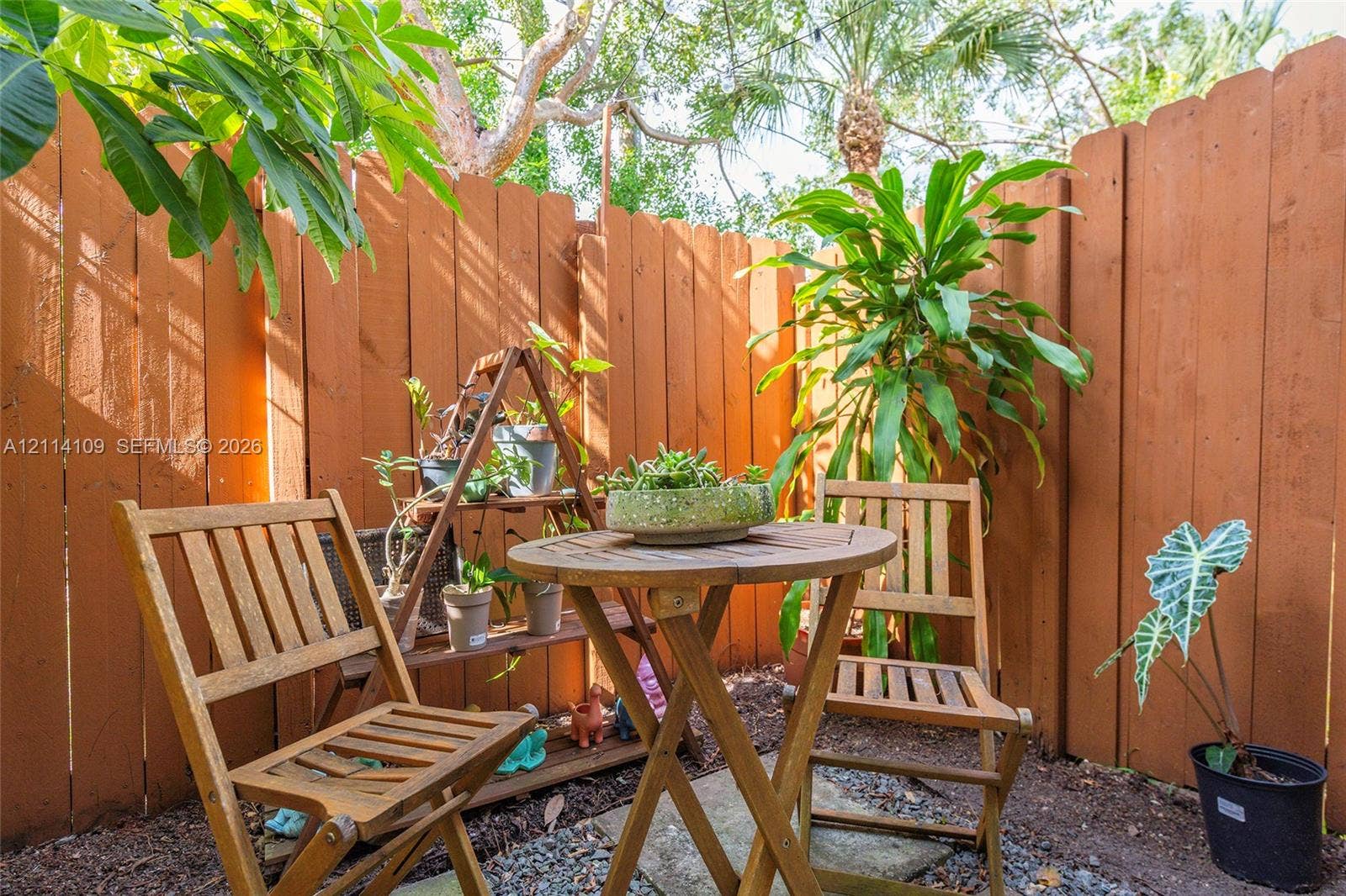 15761 SW 137th Avenue, #104, Miami, Miami, FL 33177 Private outdoor area enclosed by a vertical wood-plank fence, featuring a ground-level stone paver base and organic wood-mulch surfacing