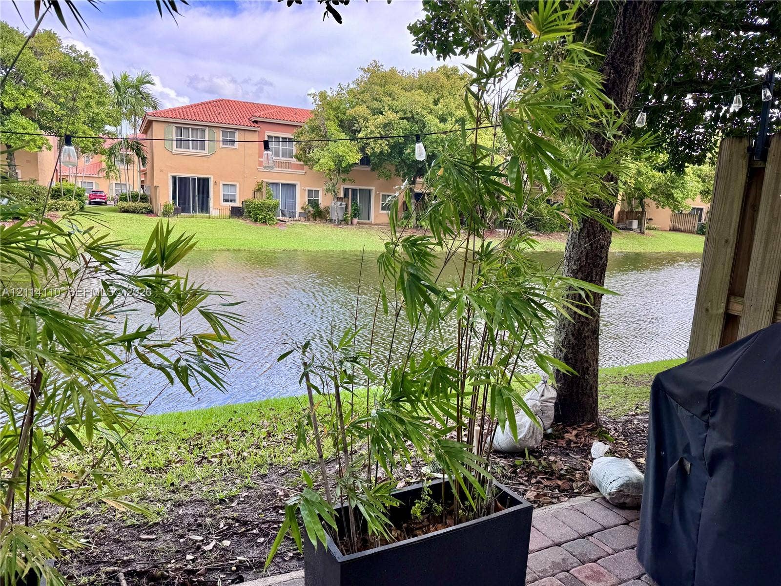 4928 Leeward Lane, #3603, Dania Beach, FL 33312 Paver patio featuring water frontage, mature trees, and overhead string lighting