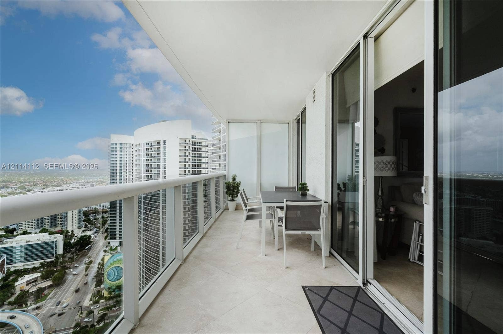 1850 S Ocean Drive, #4008, Hallandale Beach, FL 33009 Covered balcony with stone-finish flooring, glass panel railings, and full-height sliding glass doors