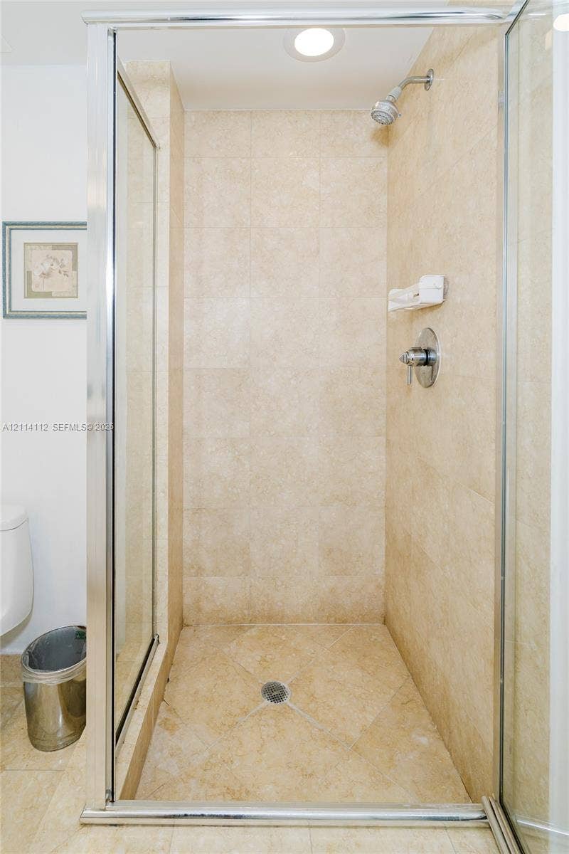 1850 S Ocean Drive, #4008, Hallandale Beach, FL 33009 Walk-in shower enclosure featuring floor-to-ceiling tile, glass door with metal frame, integrated soap dish, and chrome plumbing fixtures
