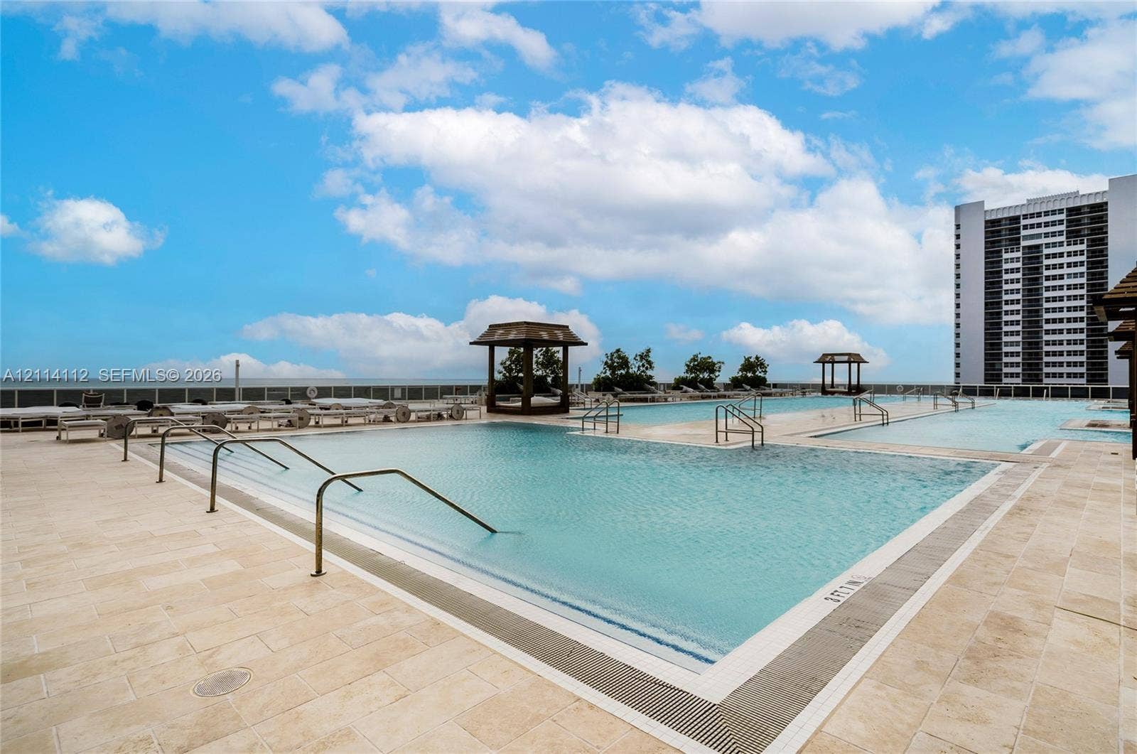 1850 S Ocean Drive, #4008, Hallandale Beach, FL 33009 Multi-level swimming pool with stone-tiled decking, metal grab rails, and wooden shaded structures