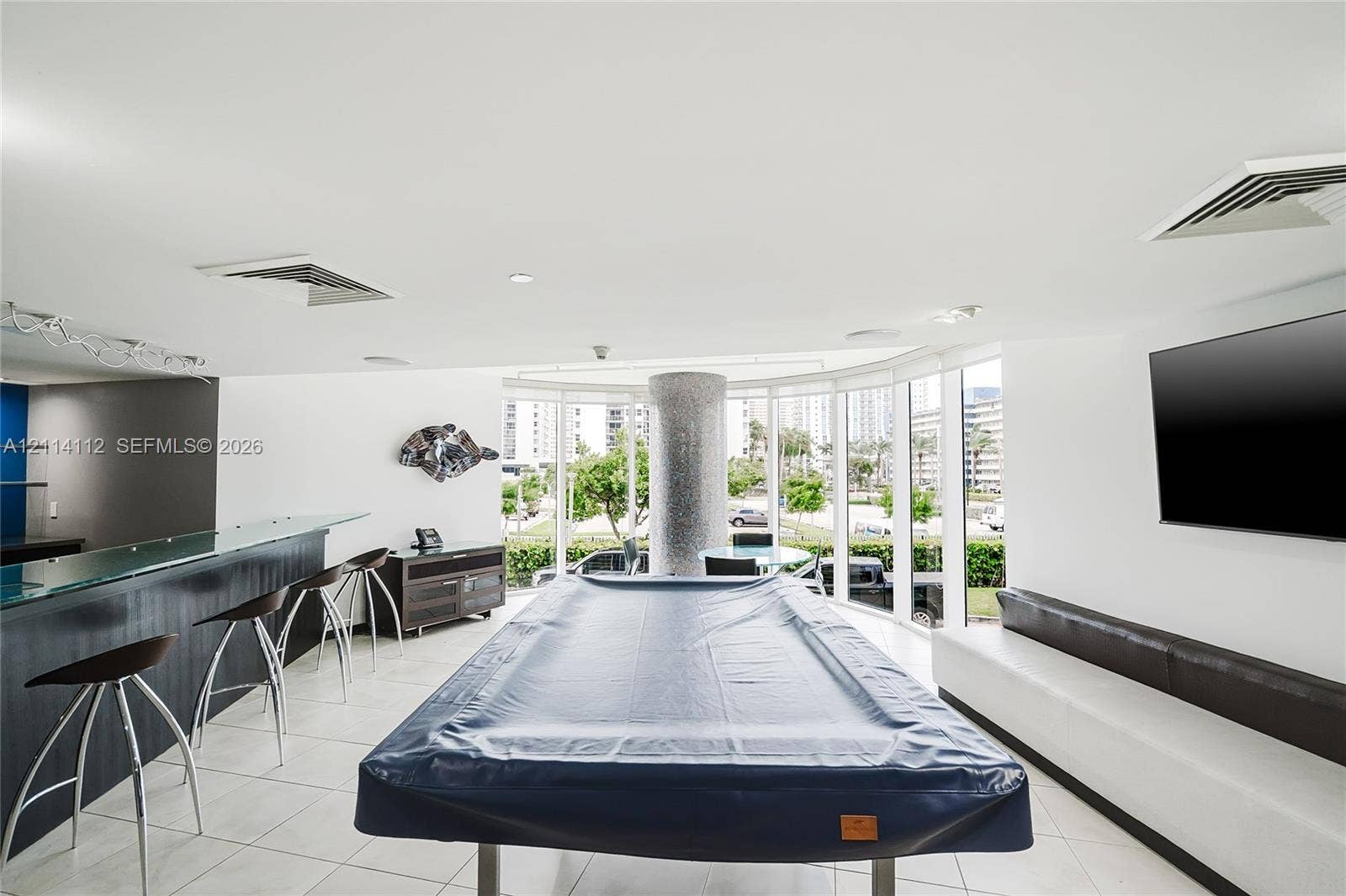 1850 S Ocean Drive, #4008, Hallandale Beach, FL 33009 Expansive recreation area featuring floor-to-ceiling glass walls, a built-in wet bar with glass countertop, tile flooring, and a stone-clad structural column