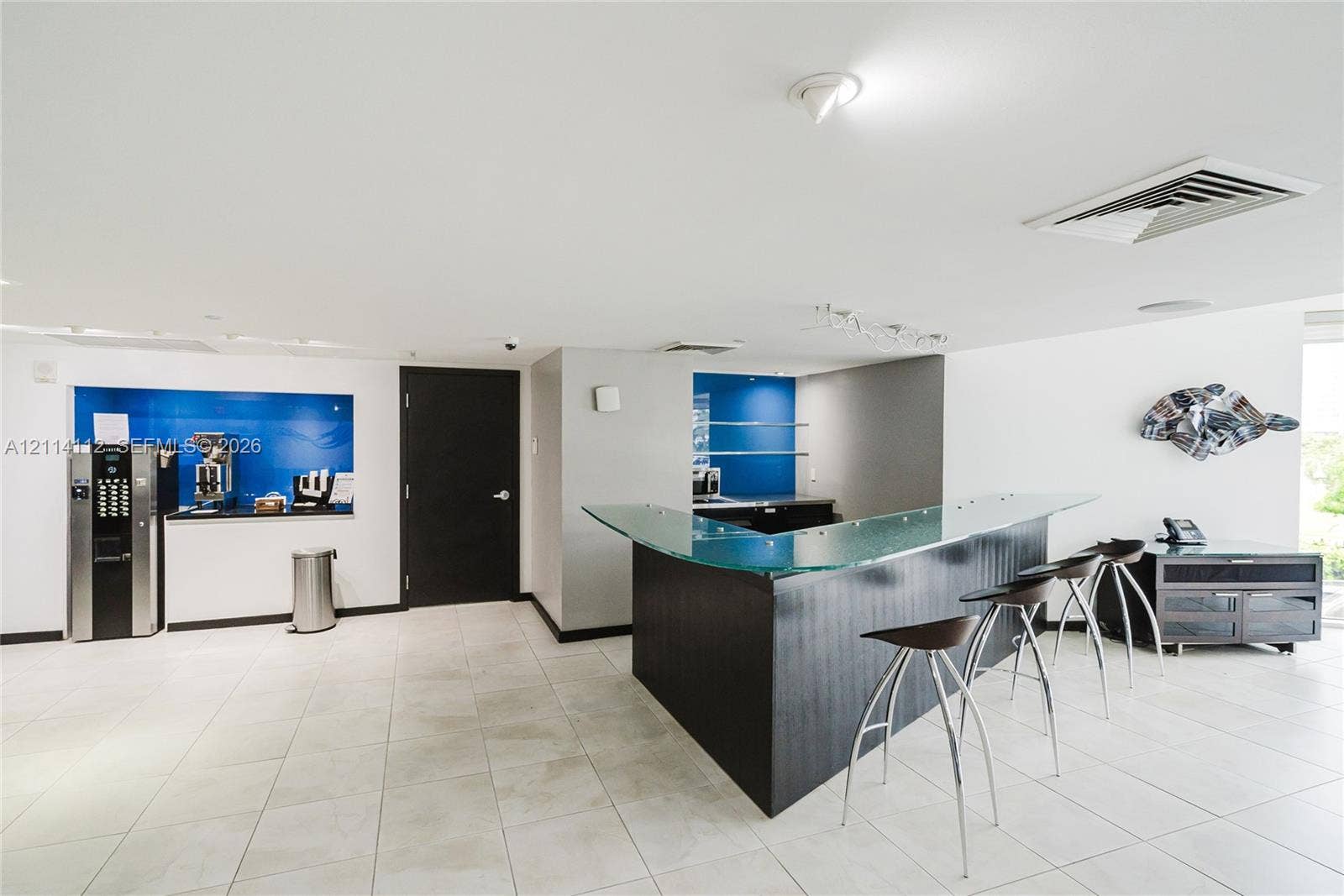 1850 S Ocean Drive, #4008, Hallandale Beach, FL 33009 Custom wet bar featuring a glass countertop, dark wood-finish cabinetry, tile flooring, and integrated blue glass backsplashes
