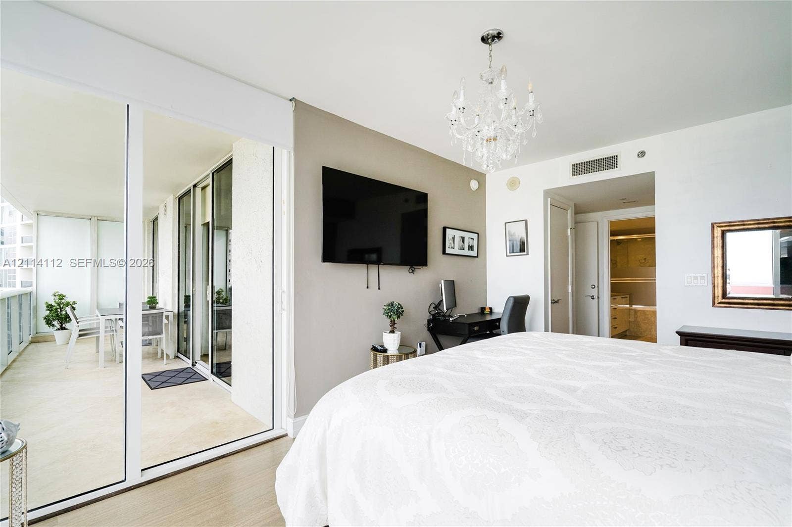 1850 S Ocean Drive, #4008, Hallandale Beach, FL 33009 Floor-to-ceiling glass sliding doors opening to an expansive covered balcony, multi-light crystal chandelier, and light-toned wood-finish flooring