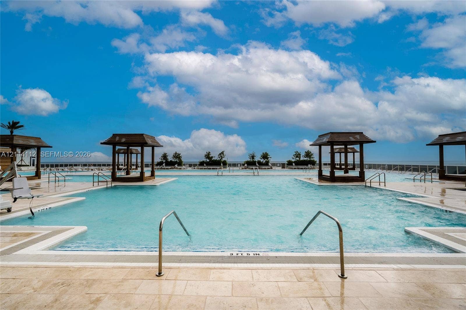 1850 S Ocean Drive, #4008, Hallandale Beach, FL 33009 Expansive swimming pool featuring built-in wooden cabanas, stone paver decking, and metal handrails