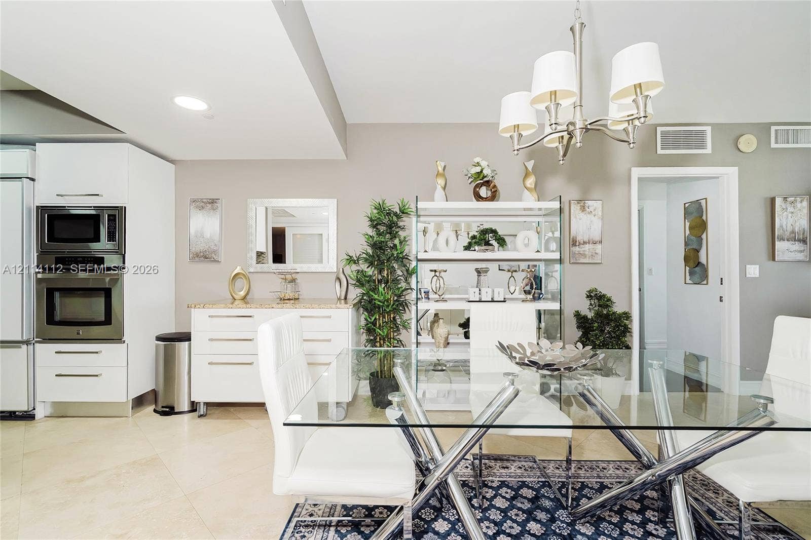 1850 S Ocean Drive, #4008, Hallandale Beach, FL 33009 Dining area featuring large-format tile flooring, a multi-arm chandelier with white fabric shades, and built-in cabinetry with stone-surface countertops
