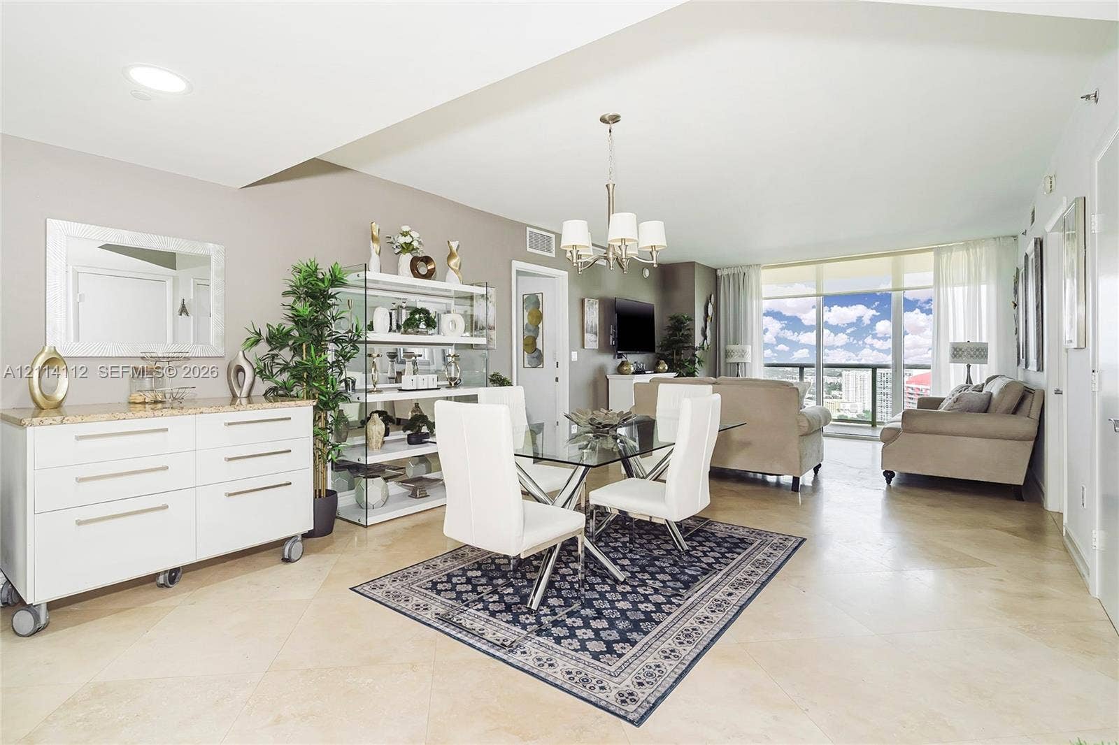 1850 S Ocean Drive, #4008, Hallandale Beach, FL 33009 Open-concept living space featuring large-format tile flooring, a multi-arm chandelier, and floor-to-ceiling windows with access to an exterior balcony