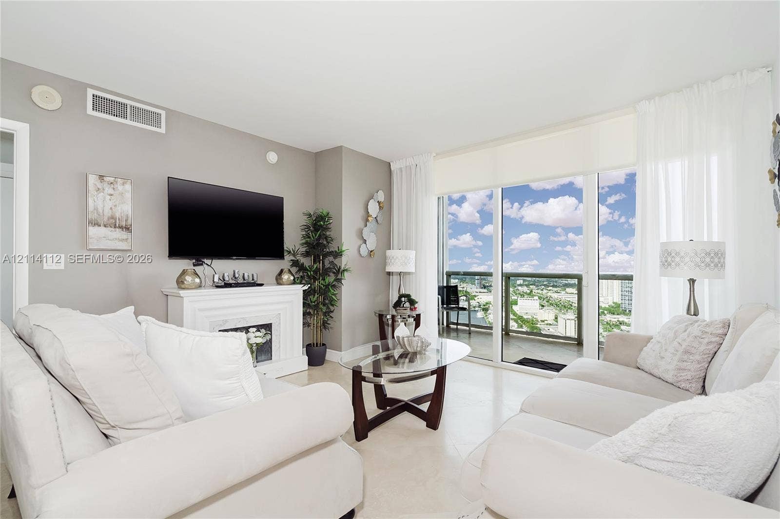 1850 S Ocean Drive, #4008, Hallandale Beach, FL 33009 Living area featuring neutral wall paint, tile flooring, a built-in decorative fireplace mantel, and full-height sliding glass doors opening to a balcony with glass railing