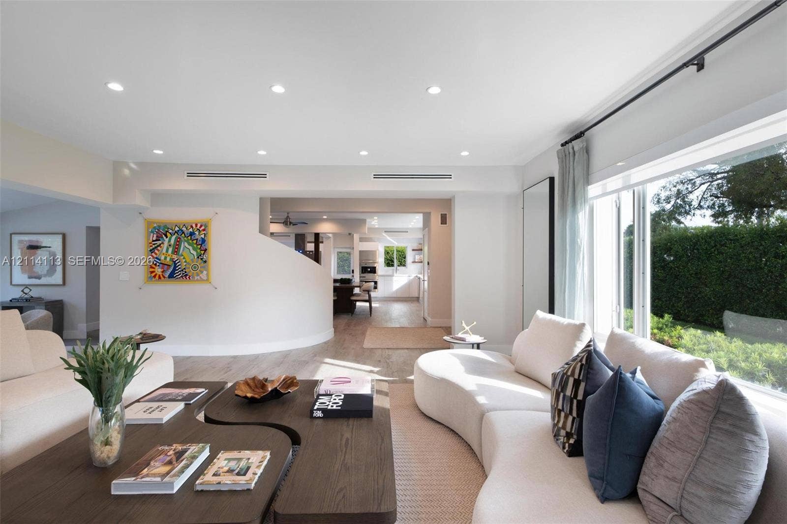 5386 Alton Road, Miami Beach, FL 33140 Open-concept interior featuring recessed lighting, curved architectural wall detail, wood-finish flooring, and expansive picture window