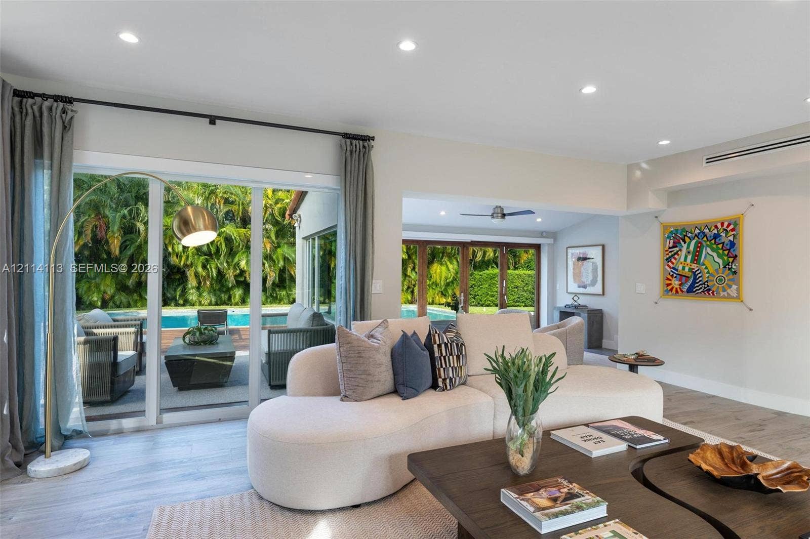 5386 Alton Road, Miami Beach, FL 33140 Living area featuring wood-finish flooring, recessed lighting, and multiple sliding glass door systems providing direct access to the outdoor pool area