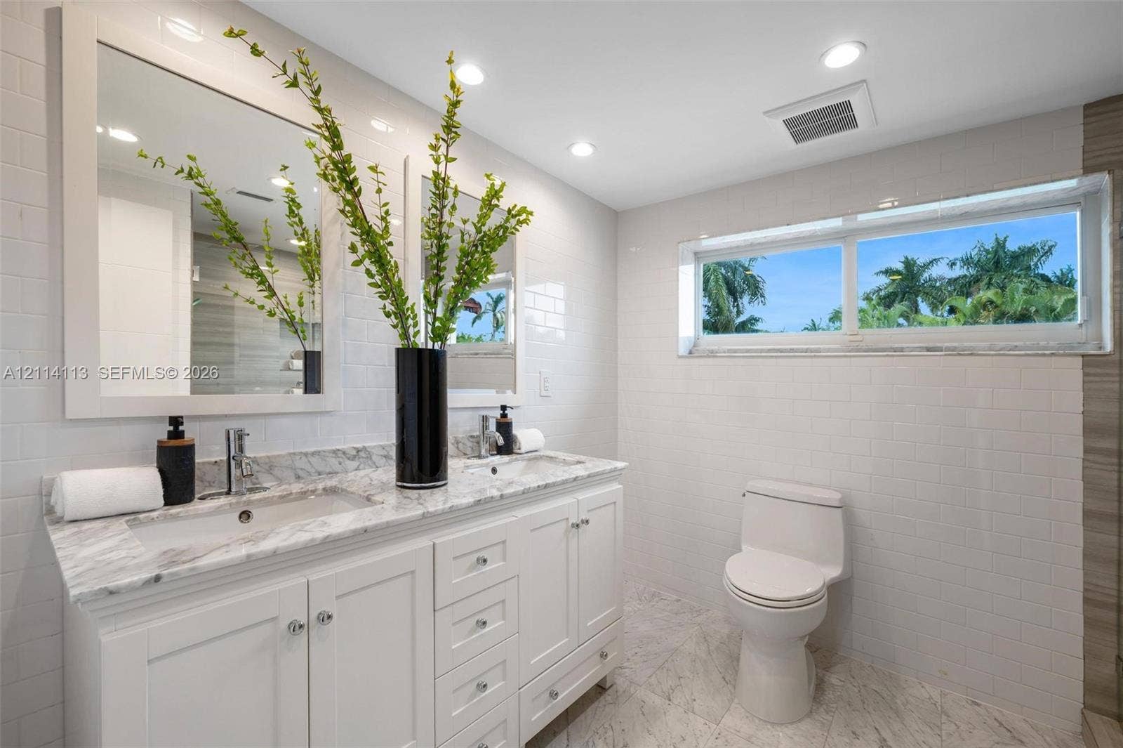 5386 Alton Road, Miami Beach, FL 33140 Double vanity with white cabinetry, stone-surface countertop, rectangular under-mount sinks, subway-tiled walls, and stone-finish flooring