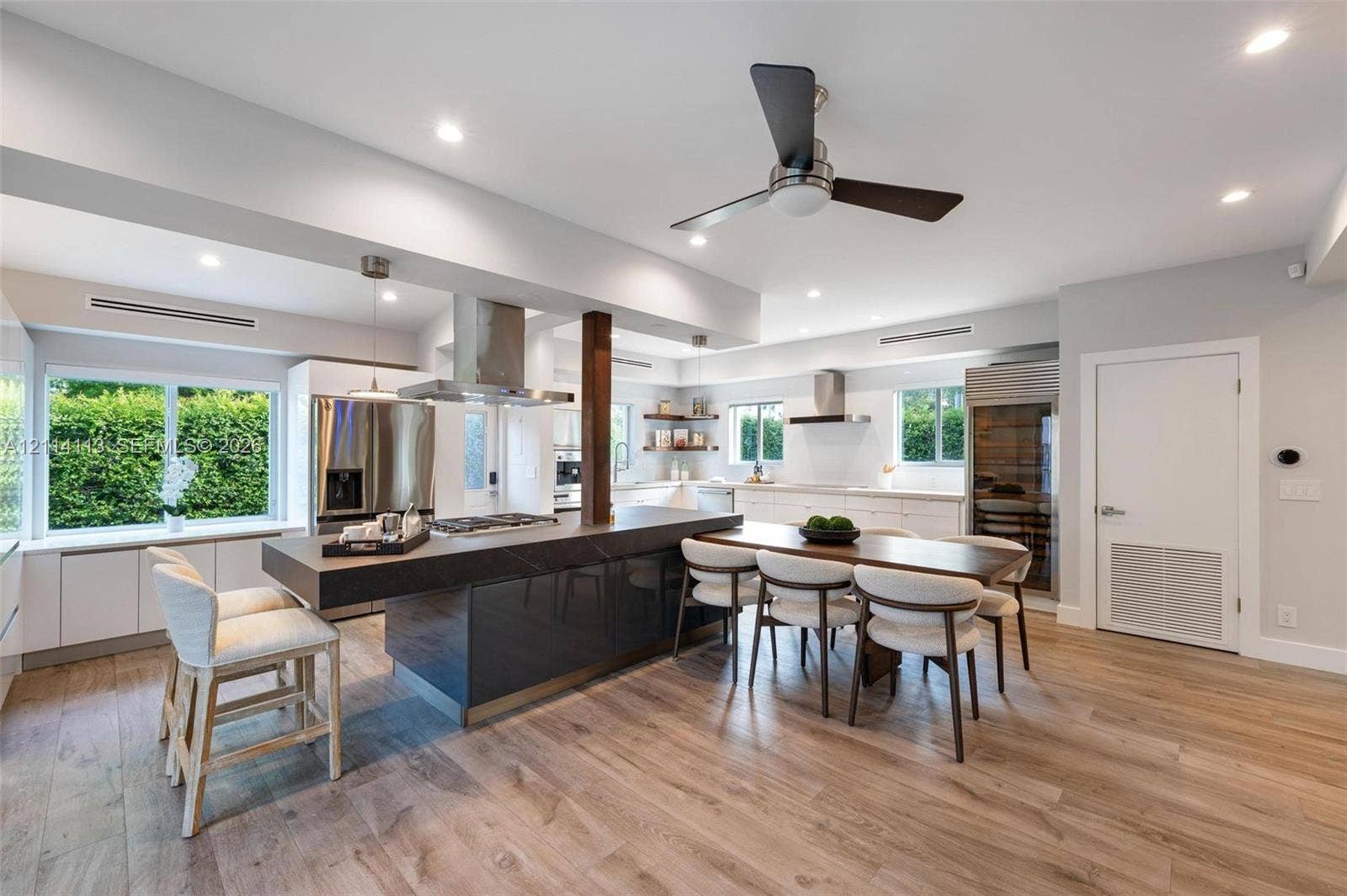 5386 Alton Road, Miami Beach, FL 33140 Gourmet kitchen featuring a large central island with stone-finish countertop, stainless steel appliances, wood-finish flooring, recessed lighting, and built-in wine storage