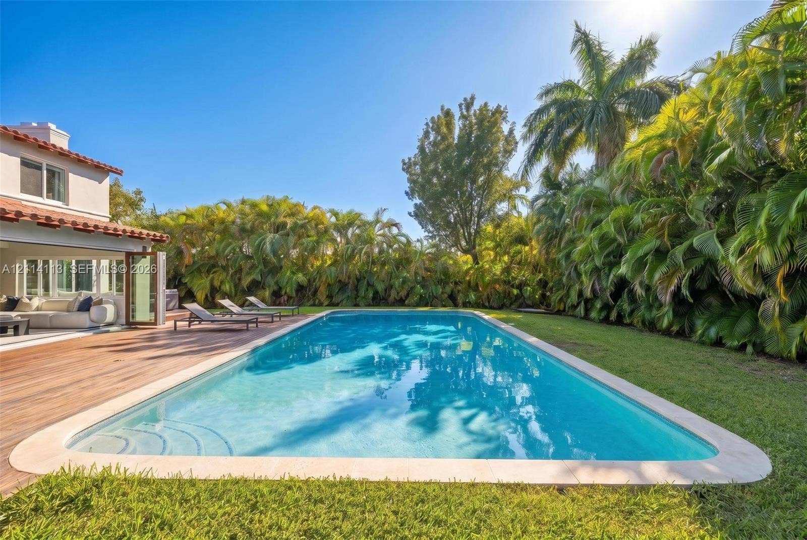 5386 Alton Road, Miami Beach, FL 33140 In-ground swimming pool with a stone coping border, wood-finish decking, and extensive perimeter greenery