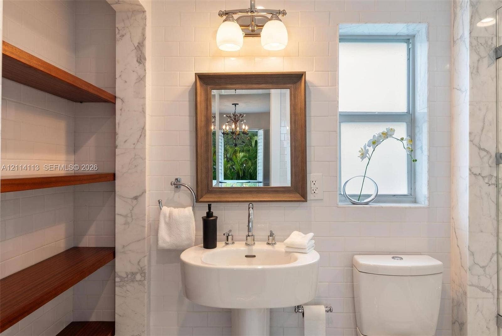 5386 Alton Road, Miami Beach, FL 33140 Bathroom featuring subway tile walls, stone-trimmed recessed shelving with wood-finish floating shelves, a pedestal sink with a chrome faucet