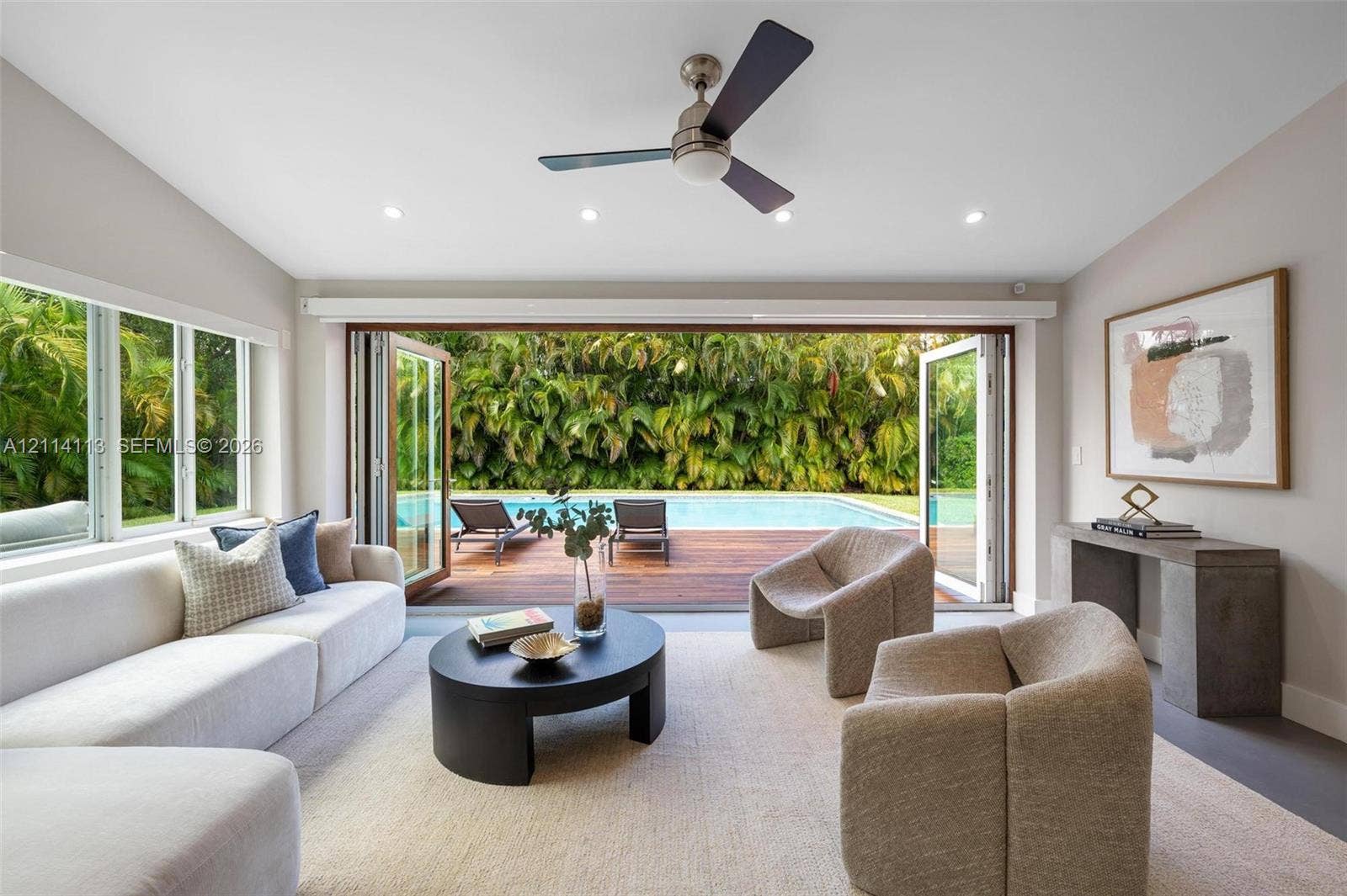 5386 Alton Road, Miami Beach, FL 33140 Multi-panel folding glass doors, recessed lighting, ceiling fan, and access to a wood-decked pool area