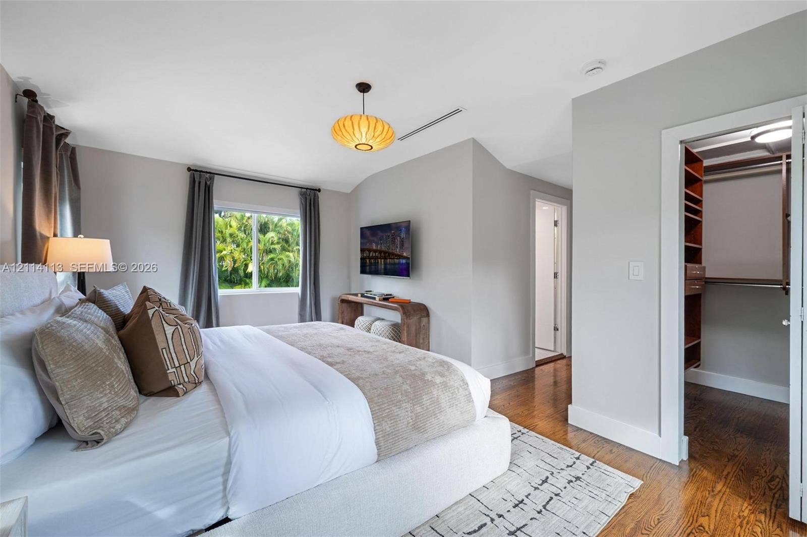 5386 Alton Road, Miami Beach, FL 33140 Natural wood flooring, custom built-in closet cabinetry and a window framing exterior foliage