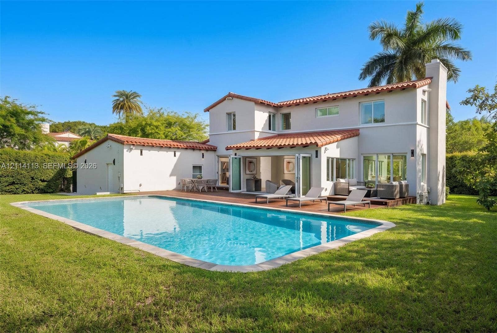 5386 Alton Road, Miami Beach, FL 33140 Mediterranean inspired exterior featuring a clay tile roof, stucco finish, in-ground swimming pool, wood-finish decking, and multi-panel folding glass doors