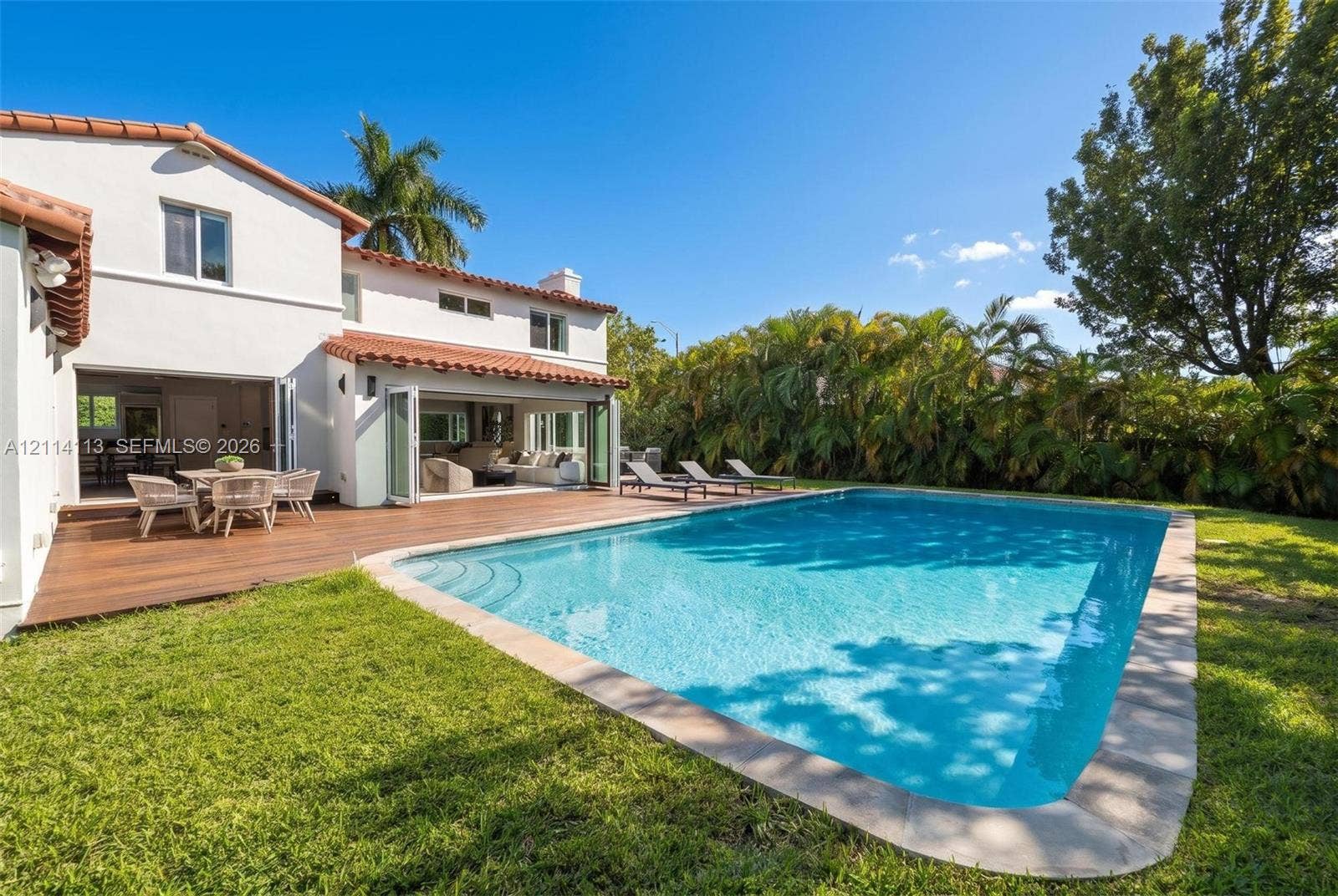 5386 Alton Road, Miami Beach, FL 33140 Stucco exterior with a clay tile roof, wood-finish decking, inground swimming pool, and folding glass wall systems