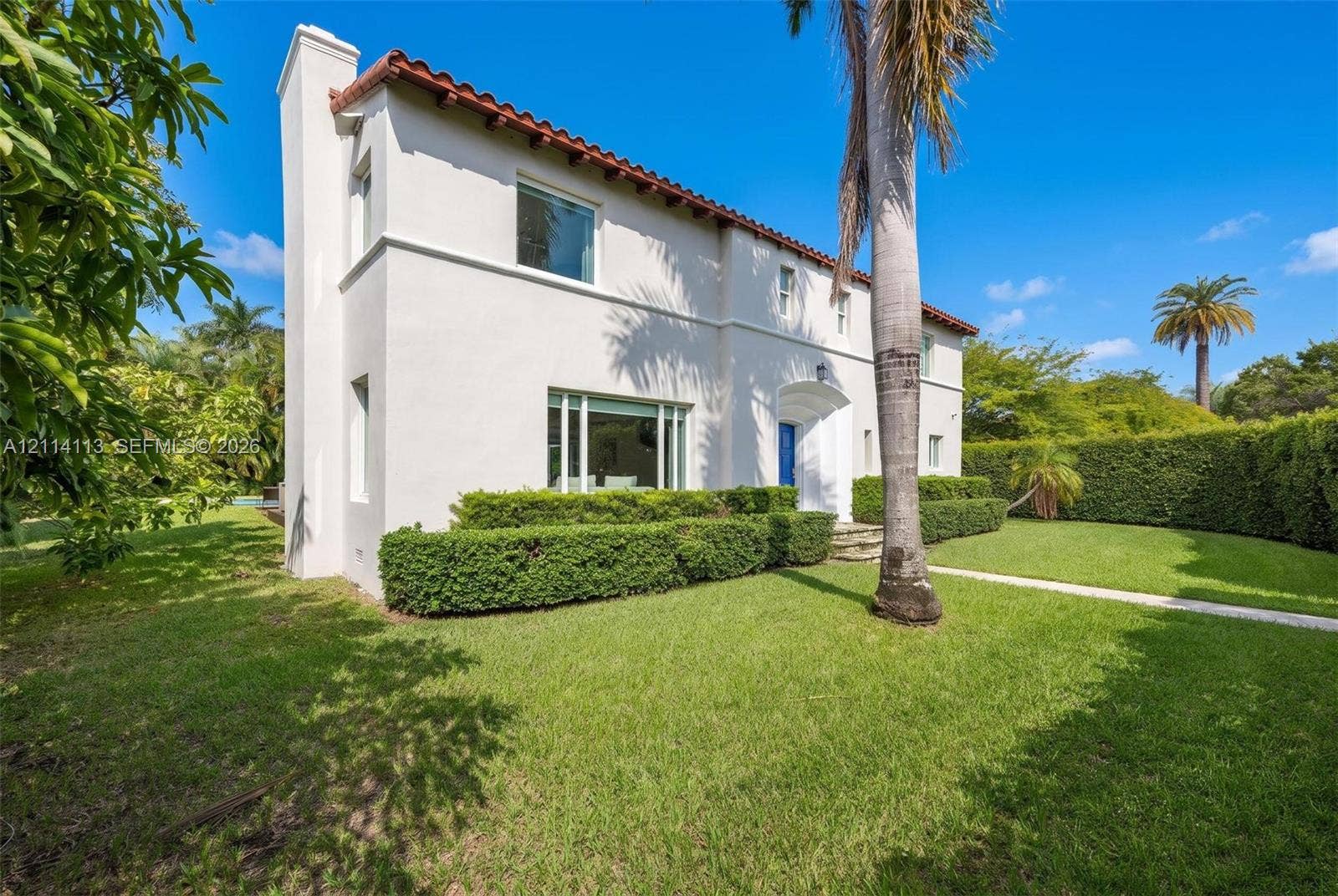 5386 Alton Road, Miami Beach, FL 33140 Stucco exterior featuring a clay tile roof, arched entryway, and manicured landscaping