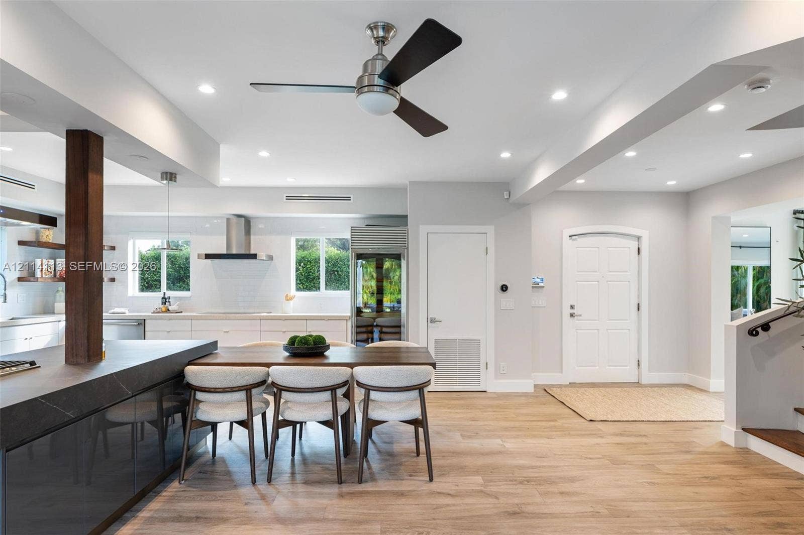 5386 Alton Road, Miami Beach, FL 33140 Open-concept interior featuring wood-finish flooring, recessed lighting, a modern ceiling fan, and a kitchen with a dark stone-top island and built-in cabinetry