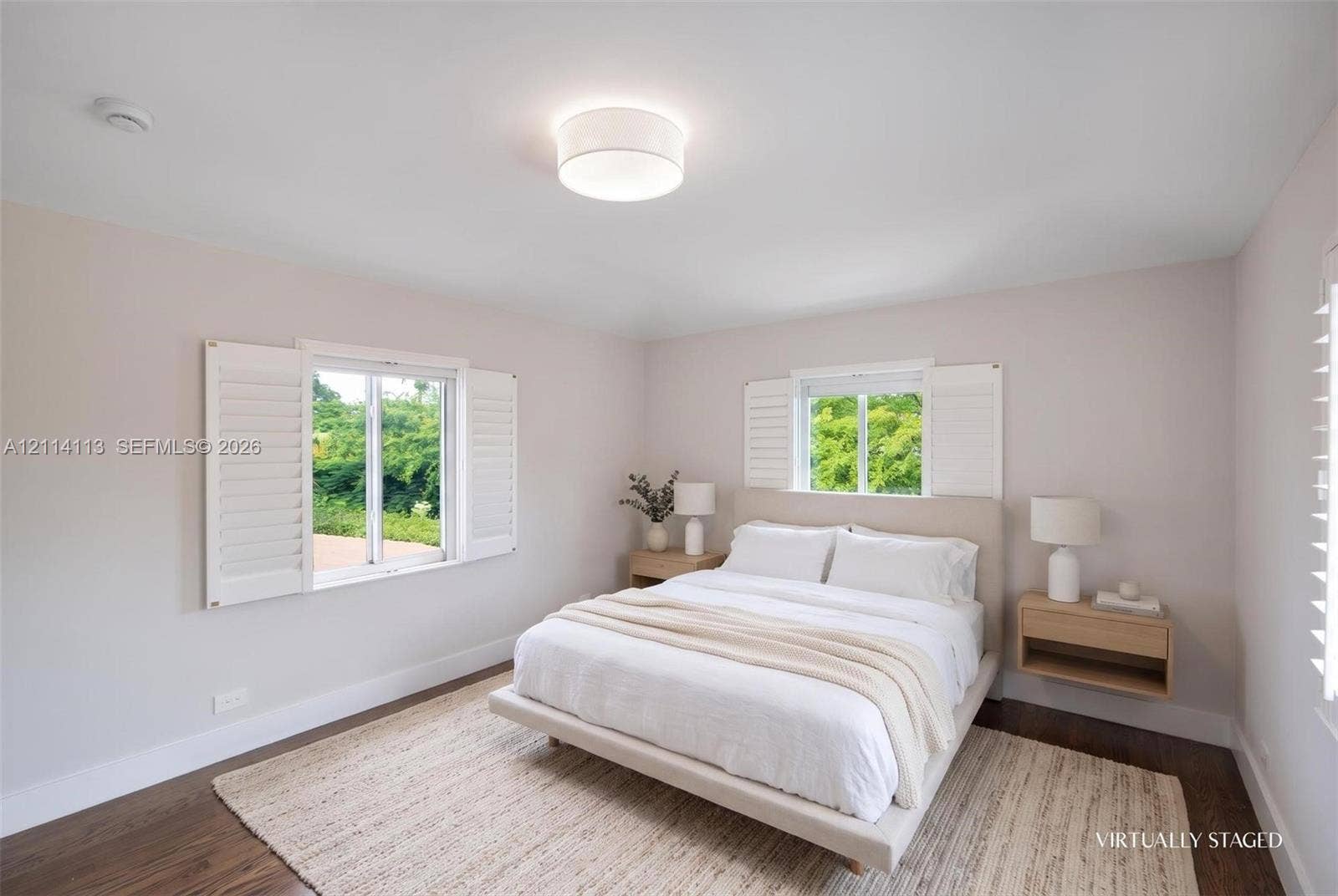 5386 Alton Road, Miami Beach, FL 33140 Room featuring wood-finish flooring, dual windows with plantation shutters, a neutral wall palette, and a circular flush-mount ceiling light
