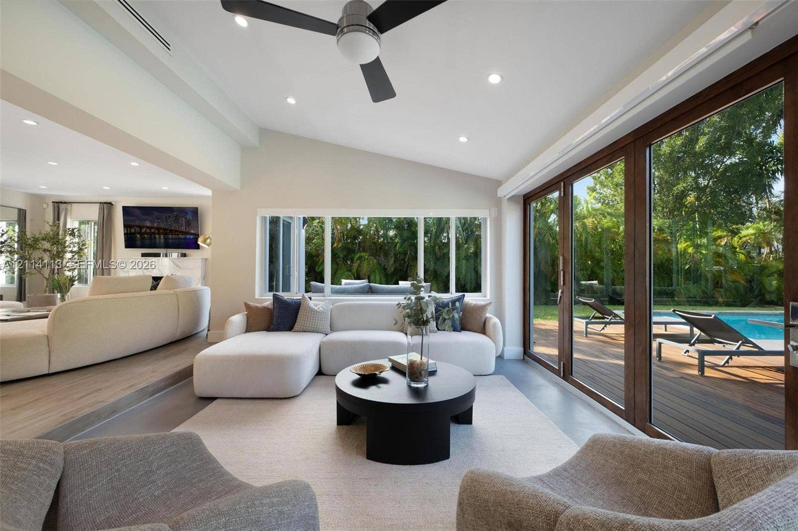 5386 Alton Road, Miami Beach, FL 33140 Living area featuring a vaulted ceiling, recessed lighting, wood-finish flooring, and expansive folding glass doors opening to the exterior deck