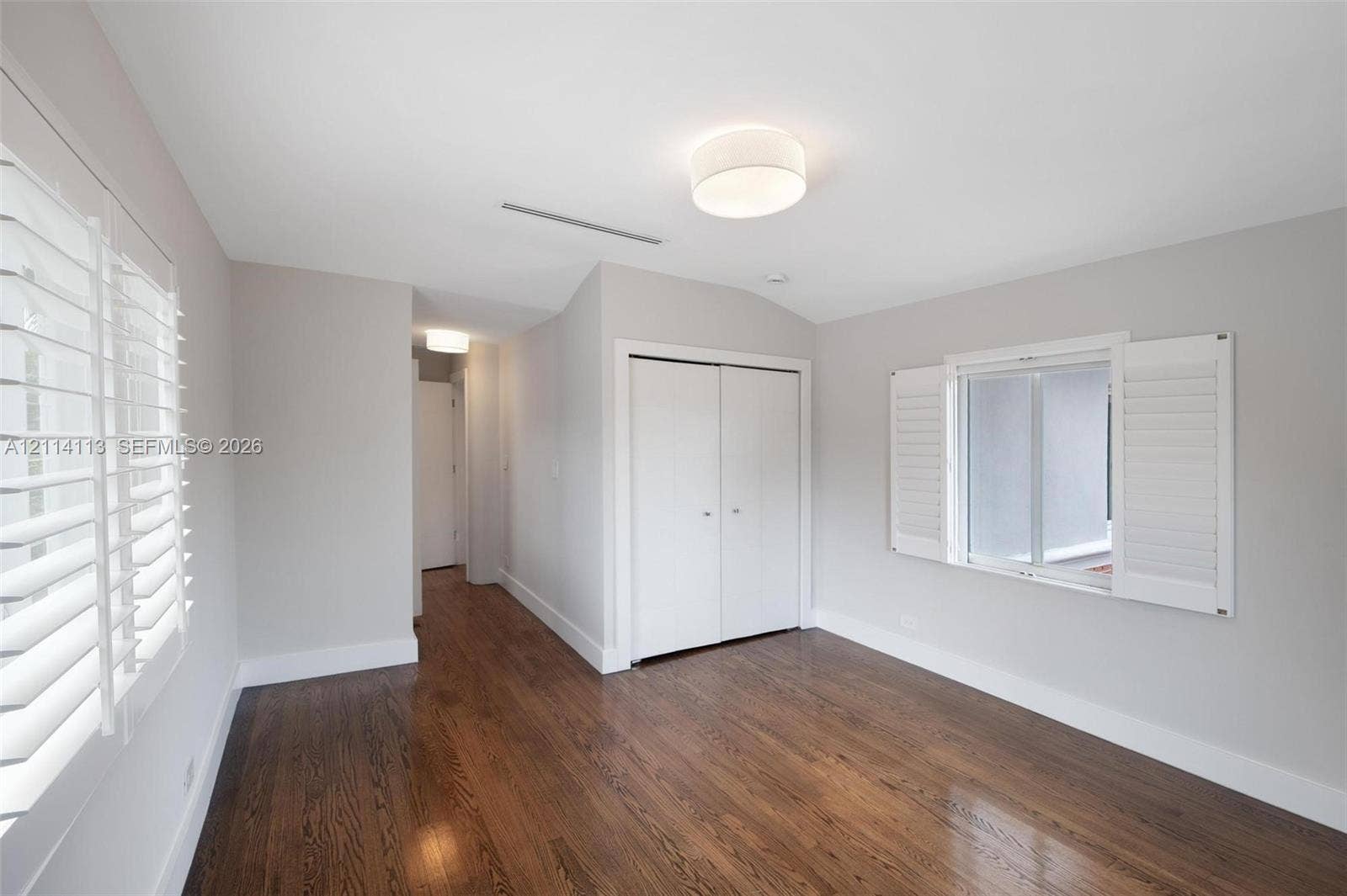 5386 Alton Road, Miami Beach, FL 33140 Room featuring wood-finish flooring, white plantation shutters, dual-door closet, and drum-style ceiling lighting