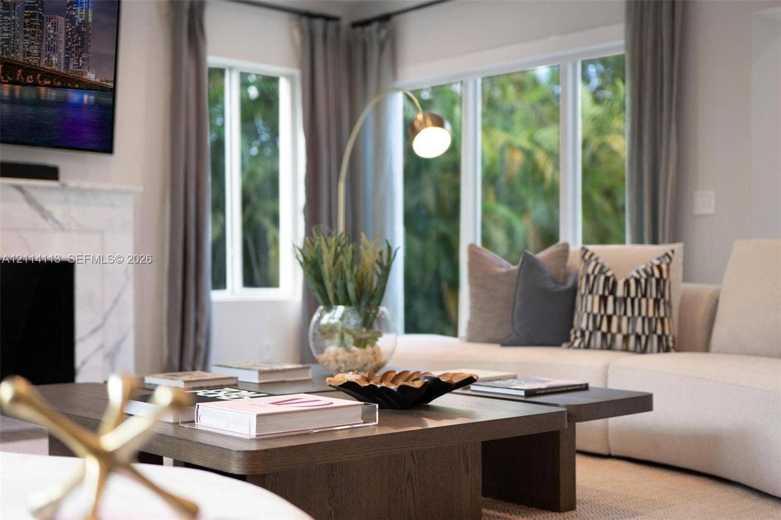 5386 Alton Road, Miami Beach, FL 33140 Living area featuring a floor-to-ceiling stone-surround fireplace, large windows, and neutral wall tones