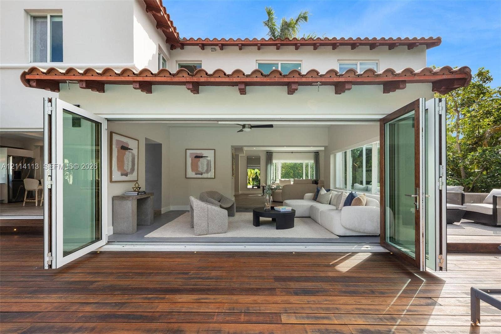 5386 Alton Road, Miami Beach, FL 33140 Stucco exterior featuring a clay tile roof, expansive wood decking, and multi-panel folding glass doors