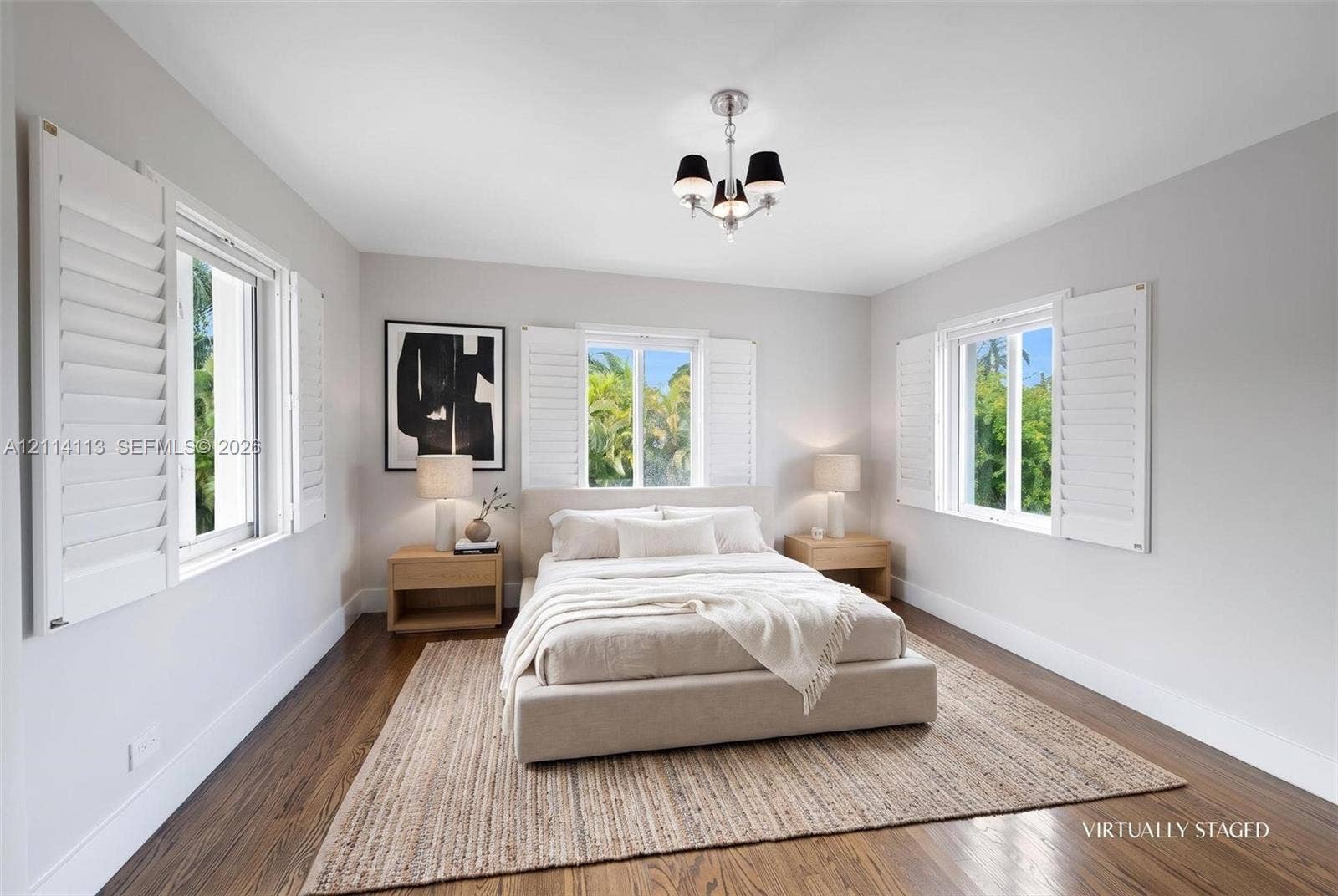 5386 Alton Road, Miami Beach, FL 33140 Light-filled room featuring wood-finish flooring, three windows with white plantation shutters