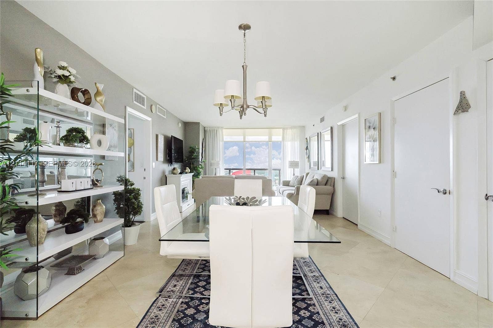 1850 S Ocean Drive, #4008, Hallandale Beach, Hallandale Beach, FL 33009 Open-concept room featuring neutral stone flooring, a multi-arm chandelier, built-in recessed display shelving, and full-height glass sliding doors