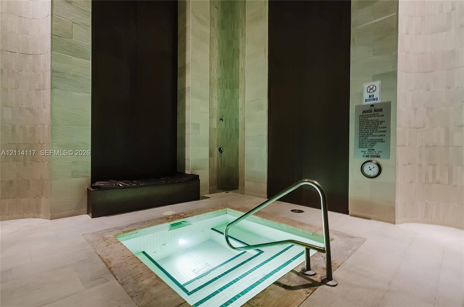 1850 S Ocean Drive, #4008, Hallandale Beach, Hallandale Beach, FL 33009 Built-in sunken spa featuring light-toned stone tile walls, contrasting dark vertical paneling, recessed step entry, and stainless steel grab rail