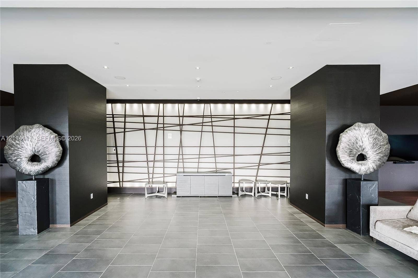 1850 S Ocean Drive, #4008, Hallandale Beach, Hallandale Beach, FL 33009 Interior space featuring oversized charcoal-toned structural columns, large-format matte tile flooring, and a decorative back-lit wall panel with geometric grid detailing