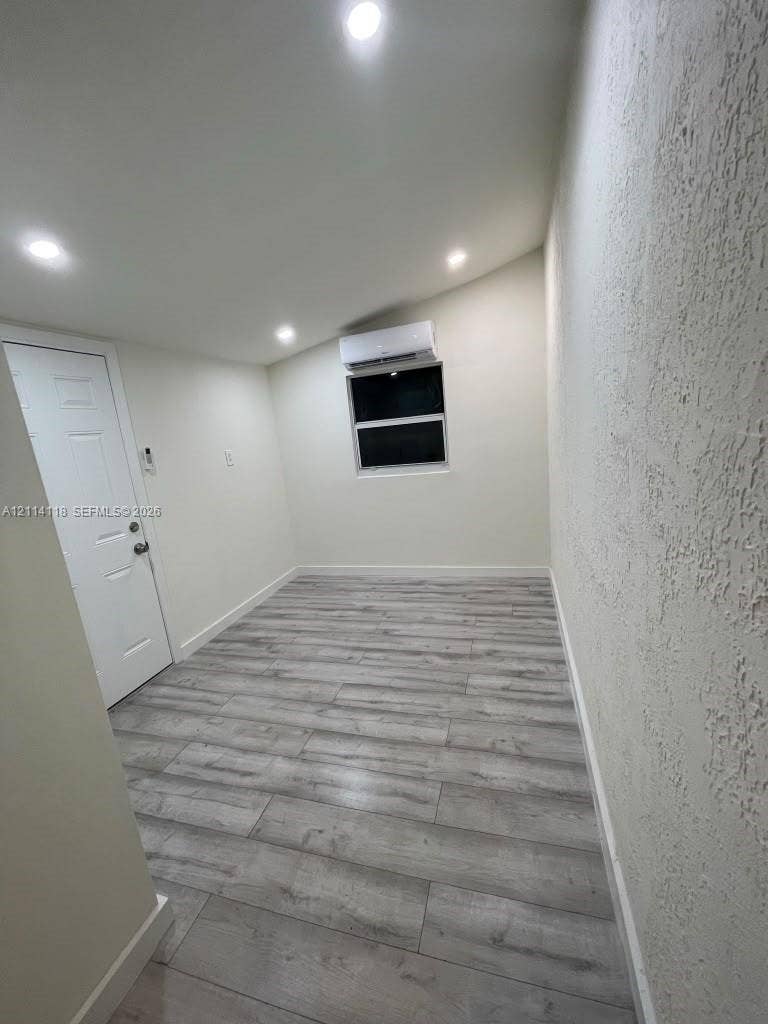 2484 SW 10th Street, #4 - eff, Miami, Miami, FL 33135 Interior room featuring wood-finish flooring, recessed lighting, a wall-mounted ductless mini-split unit, and a single-panel door