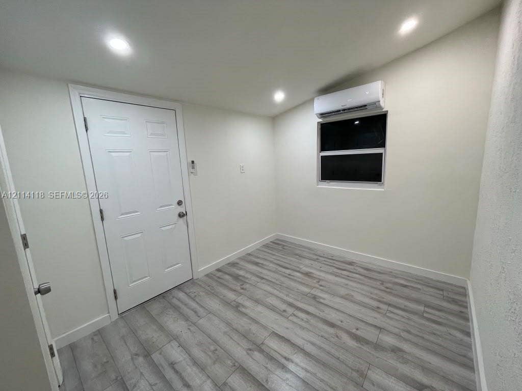 2484 SW 10th Street, #4 - eff, Miami, Miami, FL 33135 Interior space featuring wood-finish flooring, recessed lighting, wall-mounted climate control unit, and a single-hung window