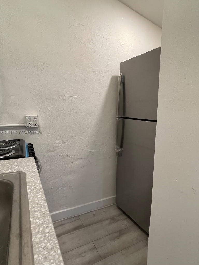 2484 SW 10th Street, #4 - eff, Miami, Miami, FL 33135 Stainless steel refrigerator, textured wall finish, speckled countertop, and wood-finish flooring