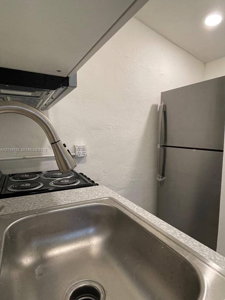 2484 SW 10th Street, #4 - eff, Miami, Miami, FL 33135 Stainless steel refrigerator, stainless steel undermount sink, gooseneck pull-down faucet, four-burner electric cooktop, and speckled-finish laminate countertops