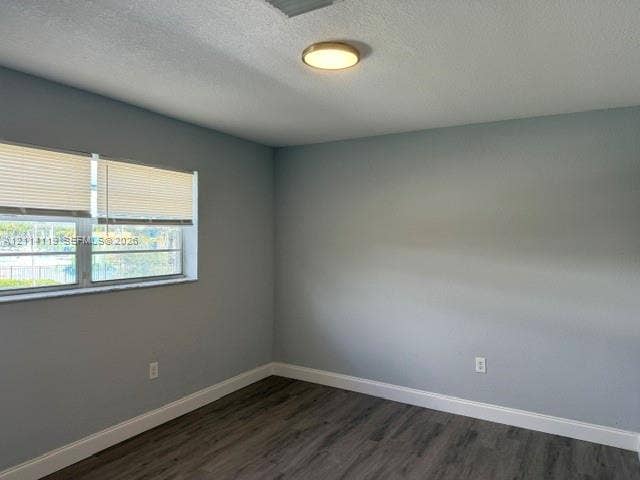 Neutral-toned walls featuring wood-finish flooring, a flush-mount circular light fixture, and horizontal window blinds