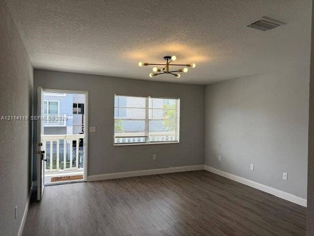 Neutral-toned interior featuring wood-finish flooring, a multi-arm sputnik-style ceiling light fixture, large windows, and a door providing access to a balcony