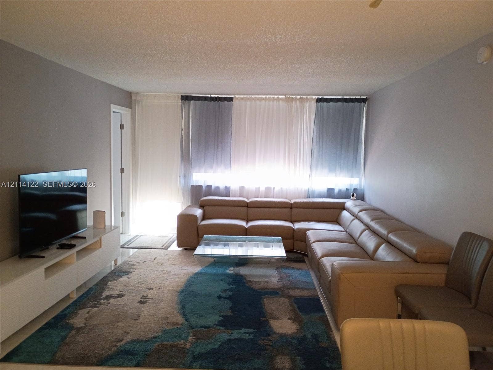 251 174th Street, #1208, Sunny Isles Beach, Sunny Isles Beach, FL 33160 Living area featuring neutral-toned walls, ceiling-height window treatments, and hard-surface flooring