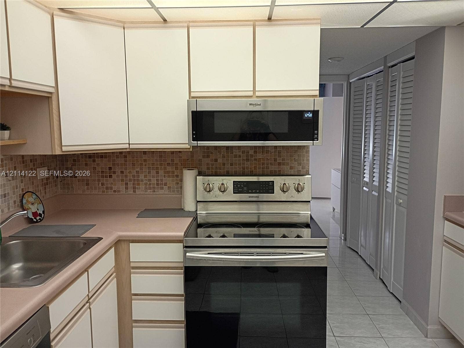 251 174th Street, #1208, Sunny Isles Beach, Sunny Isles Beach, FL 33160 Kitchen featuring flat-panel cabinetry, stainless steel oven with range, matching over-the-range microwave, mosaic tile backsplash, and light-tone countertops