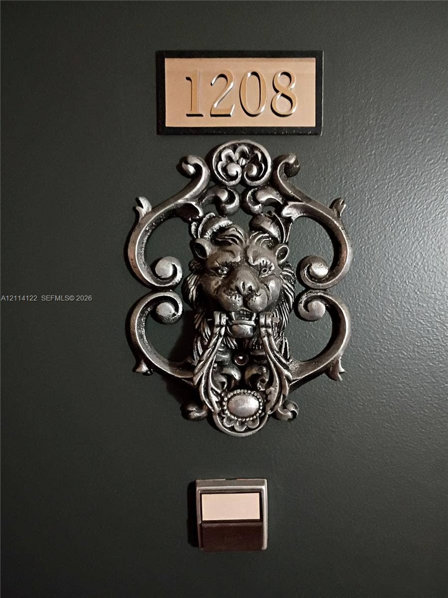 251 174th Street, #1208, Sunny Isles Beach, Sunny Isles Beach, FL 33160 Dark-toned entry door featuring a metallic lion-head door knocker, custom rectangular house number plaque, and a built-in metal doorbell button